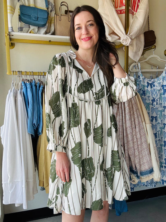 Introducing our Guacamole Floral Puff Sleeve Dress! With a vibrant green floral print and striped background, this short dress flatters in an a-line silhouette. Featuring 3/4 sleeves and a split neck with tie, it's perfect for both casual outings and special occasions. Dress to impress (and make your friends green with envy) with this stylish and playful piece!
