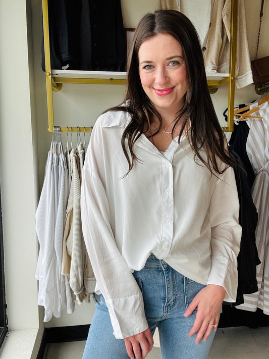 This classic white woven blouse features an elegant adjustable cross tie back design for a customizable fit. Complete with functioning buttons, this versatile piece transitions effortlessly from professional settings to casual outings. The timeless silhouette ensures enduring style while the thoughtful details elevate its everyday wearability.