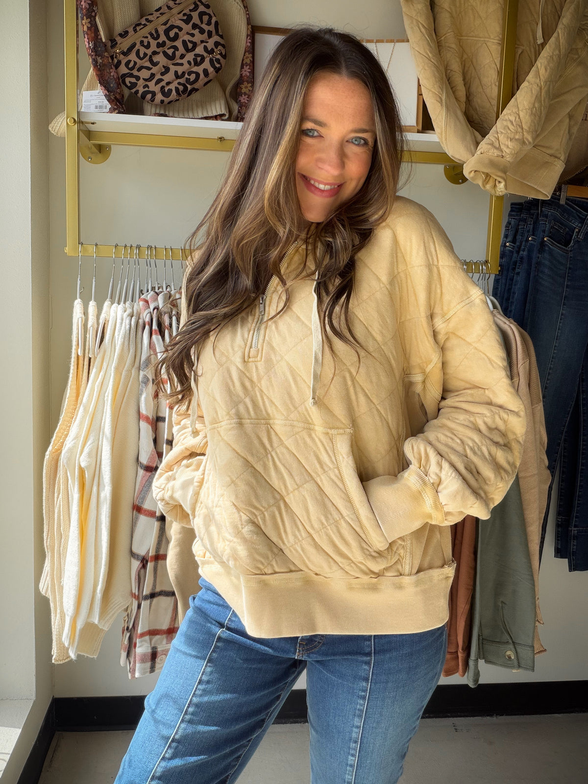 Model wearing a dandelion yellow quilted quarter-zip hoodie with a drawstring hood and kangaroo pocket.