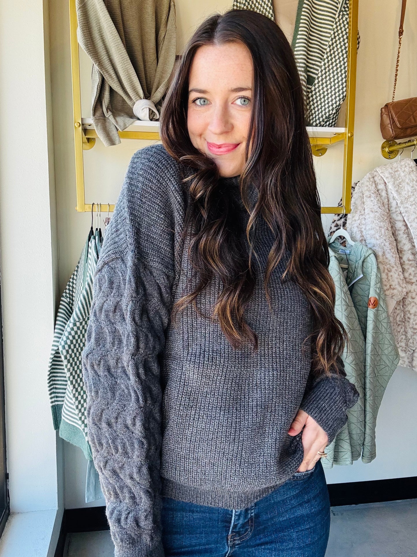 Umgee

Wrap yourself in cozy charm with this classic grey turtleneck sweater. Featuring playful cable knit sleeves, it adds a touch of texture and warmth to your look. Perfect for chilly days, this sweater combines comfort and style effortlessly.