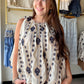 The tank that travels well — from the farmers market to dinner out. The Ivory Black Embroidered Tank features a striking ethnic-inspired vertical motif in a classic ivory and black palette that feels both timeless and effortlessly boho-chic.

A gathered neckline adds soft, feminine detail, while the relaxed woven fit keeps things breezy and comfortable all day. The linen-blend fabric gives it that natural, lived-in texture that only gets better as the day goes on.

Tuck it into wide-leg trousers, knot it ov
