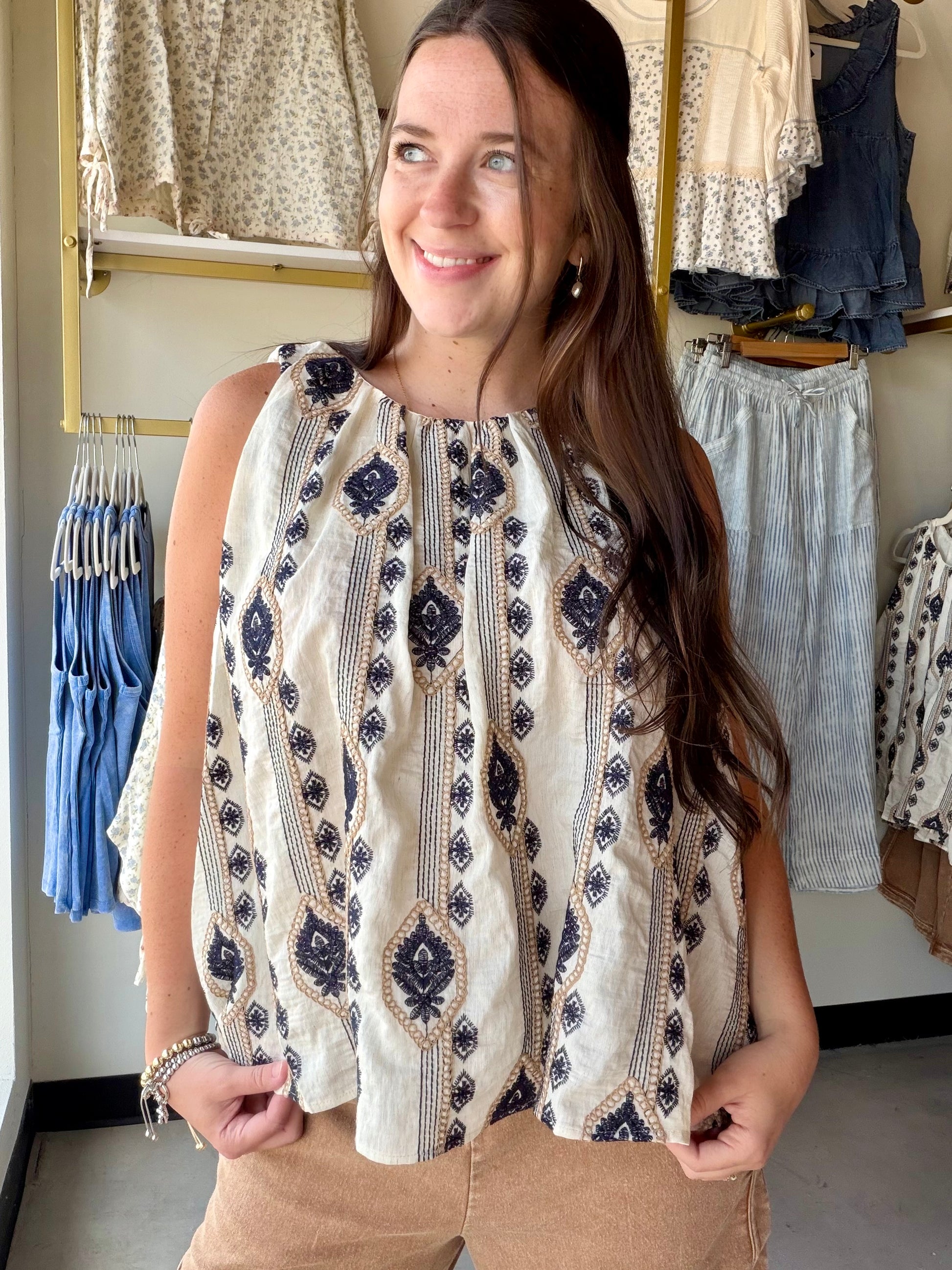 The tank that travels well — from the farmers market to dinner out. The Ivory Black Embroidered Tank features a striking ethnic-inspired vertical motif in a classic ivory and black palette that feels both timeless and effortlessly boho-chic.

A gathered neckline adds soft, feminine detail, while the relaxed woven fit keeps things breezy and comfortable all day. The linen-blend fabric gives it that natural, lived-in texture that only gets better as the day goes on.

Tuck it into wide-leg trousers, knot it ov