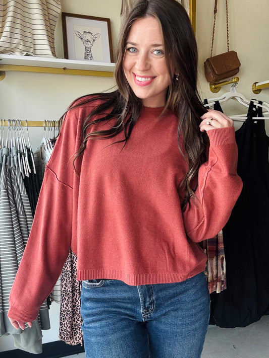 This Heather Rust Drop Sleeve Sweater features a high neckline and dropped shoulder design, offering a relaxed fit that combines comfort with contemporary style. Its pullover construction makes it easy to wear, while the soft fabric ensures warmth and versatility for layering in cooler weather. Ideal for a polished yet casual look.