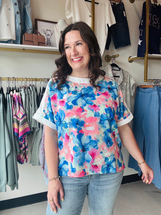 Elevate your everyday style with this vibrant watercolor floral blouse featuring chic contrast detailing and a breezy, woven fit. Flattering side slits and an artistic print make it the ultimate choice for effortless summer elegance and all-day comfort.
