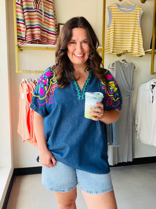 The details are everything on this one. The Chambray Vibrant Sleeve Dolman Top by Umgee is a charming embroidered denim blouse with short puff sleeves, elastic cuffs, and a split V-neckline trimmed with delicate embroidery. The contrast stitching adds an artisan touch that makes this top feel truly special.

Lightweight and breathable in a cotton-blend chambray, it pairs beautifully with white denim, linen trousers, or a flowy midi skirt for an effortlessly put-together warm-weather look.

Split V-neck with