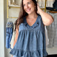 Effortless femininity, no effort required. The Dark Chambray Ruffle Tank is the kind of warm-weather piece that looks like you tried — without actually trying at all.

A ruffled V-neckline and flirty tiered babydoll silhouette give it that soft, romantic energy, while the lightweight chambray fabric keeps things cool and breezy from morning to evening. The ruffled hem adds movement with every step, making this one just as good for a weekend brunch as it is for a summer evening out.

Wear it alone, tuck the 