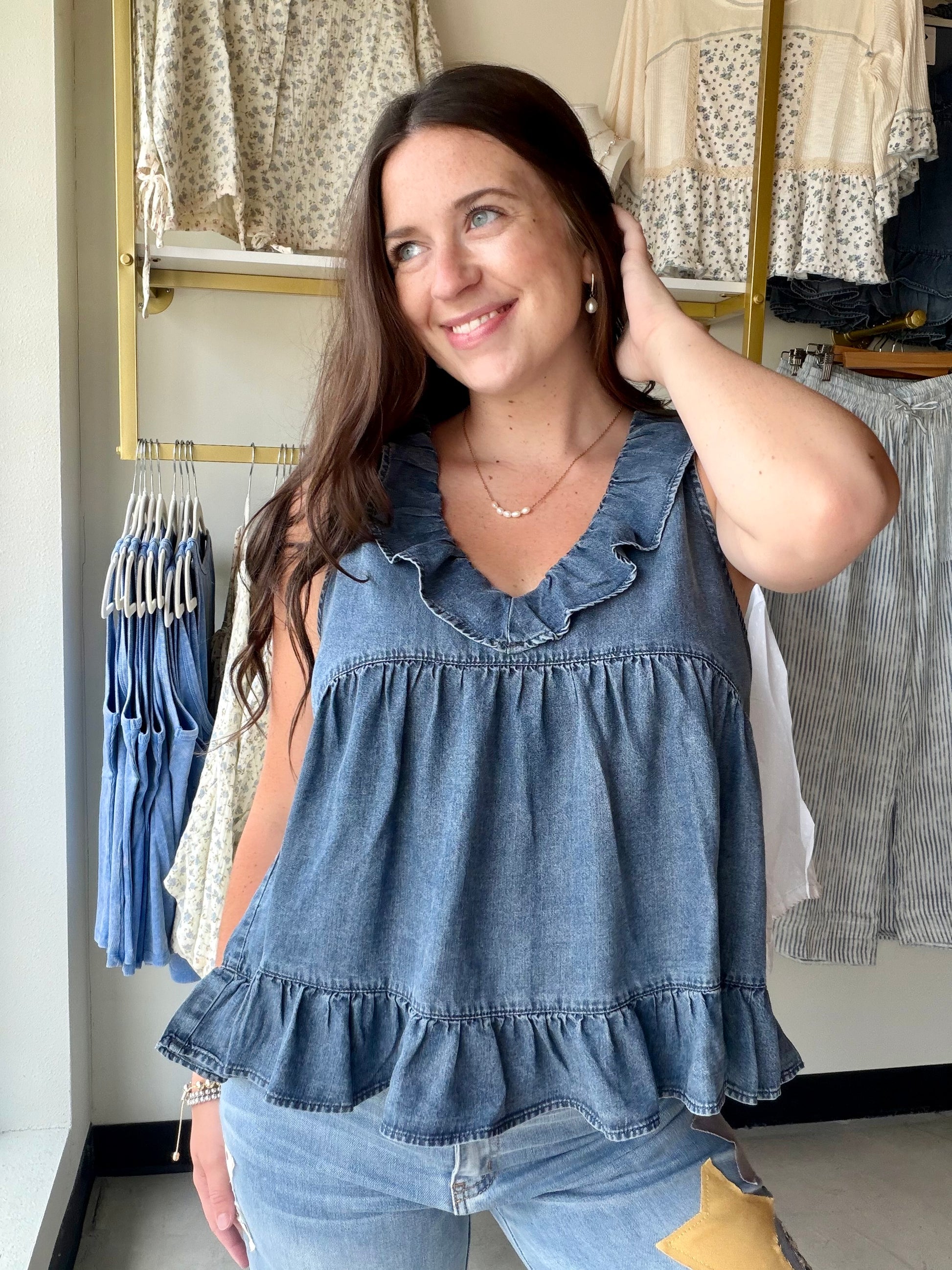 Effortless femininity, no effort required. The Dark Chambray Ruffle Tank is the kind of warm-weather piece that looks like you tried — without actually trying at all.

A ruffled V-neckline and flirty tiered babydoll silhouette give it that soft, romantic energy, while the lightweight chambray fabric keeps things cool and breezy from morning to evening. The ruffled hem adds movement with every step, making this one just as good for a weekend brunch as it is for a summer evening out.

Wear it alone, tuck the 