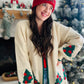 Wrap yourself in holiday cheer with this charming cream cardigan featuring festive Christmas trees adorned with twinkling stars. The playful design is elevated by crisp green trim detailing that frames the neckline and cuffs, while cozy ribbed fabric throughout adds texture and comfort. Perfect for spreading seasonal joy whether you're decorating, gathering with loved ones, or simply embracing the festive spirit in style. A wardrobe essential that brings warmth and whimsy to your holiday rotation.

Fantasti