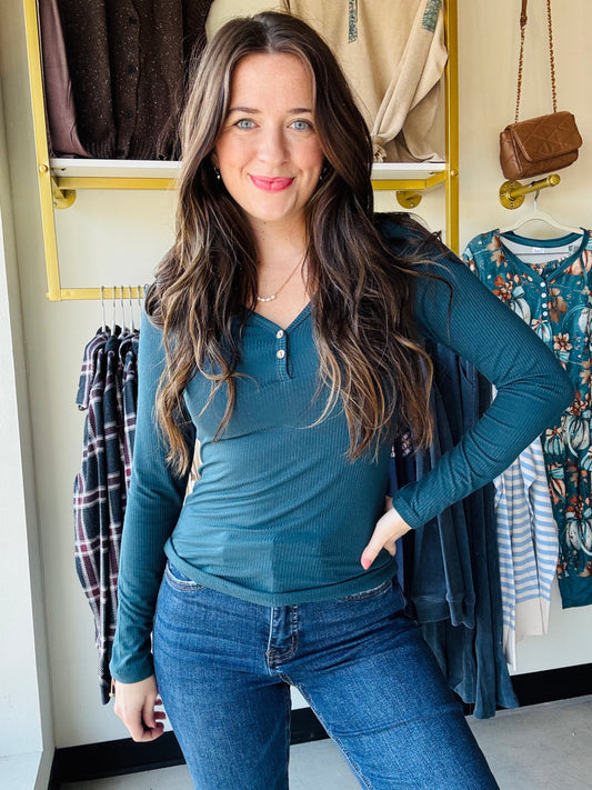 Embrace cozy charm with this Dark Teal Button V Neck! Featuring a flattering V-neckline and two cute buttons, its ribbed texture adds playful detail. The long sleeves and relaxed fitted silhouette make it perfect for layering or solo style moments. Imported for a unique touch, this top pairs effortlessly with your favorite jeans or skirts for an easygoing, fun vibe.

Yelete