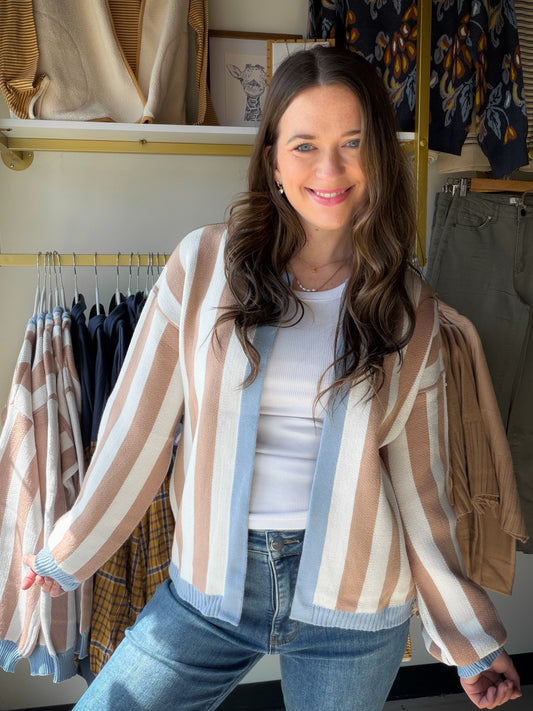Some cardigans are functional. This one is a whole look. The&nbsp;Denim &amp; Mocha Accent Cardigan wraps you in soft, cozy knit while a bold colorblock stripe in denim blue, warm mocha, and cream does all the talking. The kind of layer you reach for on repeat — whether you're running errands in style or curling up with coffee.

Why You'll Love It

Vertical colorblock stripe in mocha, cream &amp; dusty blue — effortlessly editorial
Relaxed, boxy fit with a cropped hip-length hem — flattering on every frame

