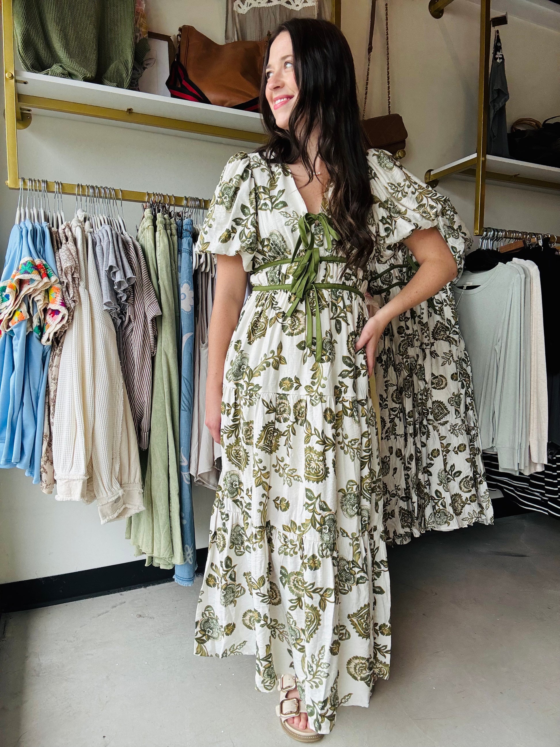 Entro

This Olive Floral Midi Dress combines elegance and comfort with its short bubble sleeves and flattering elasticated waist at the back. Crafted from lightweight woven fabric, it features a delicate floral print and a contrasting bow accent at the front for a refined touch. Fully lined and non-sheer, it offers modest coverage while side pockets add practical convenience. Ideal for stylish, effortless wear throughout the day.