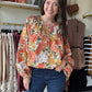 Bibi

This orange floral blouse features exaggerated balloon sleeves and a front tie detail, combining bold design with feminine elegance. Its lightweight fabric ensures comfort and breathability, while the vibrant print adds a fresh, stylish touch to any outfit. Ideal for elevating both casual and dressier looks with a confident, expert flair.