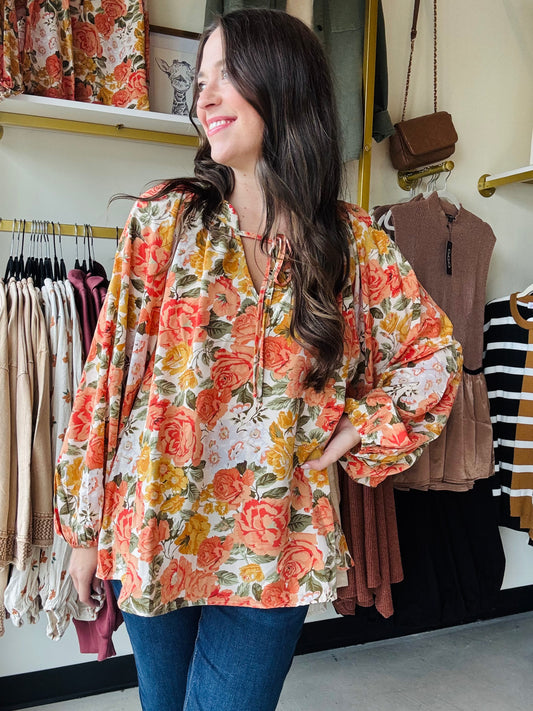Bibi

This orange floral blouse features exaggerated balloon sleeves and a front tie detail, combining bold design with feminine elegance. Its lightweight fabric ensures comfort and breathability, while the vibrant print adds a fresh, stylish touch to any outfit. Ideal for elevating both casual and dressier looks with a confident, expert flair.