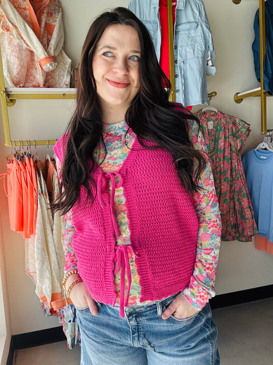 Staccato&nbsp;

Elevate your layering game with this striking fuchsia crochet vest. Featuring double bow ties at the front and an intricate crochet-like texture, this piece blends playful elegance with versatile style. The lightweight construction makes it perfect for pairing over your favorite tees or dresses, while the bold color adds instant personality to any outfit. A modern take on the classic vest silhouette.