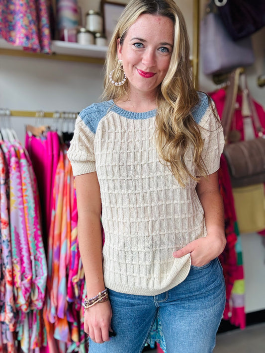 Elevate your wardrobe with our Birdseye Texture Raglan Sweater. In gorgeous blue and cream, this short sleeve sweater flawlessly transitions you from summer to fall. The high neckline and subtle puff sleeve detail add a touch of sophistication, perfect for the office or a coffee date.  Bibi Brand