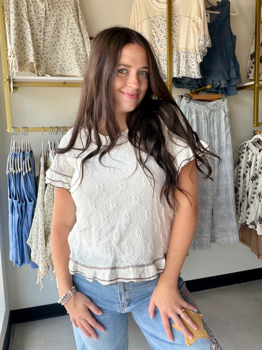 Bibi

The little details make all the difference. The Ivory Eyelet Detail Ruffle Top is a sweet, feminine top that earns its compliments through the finer things — delicate eyelet fabric contrast, ruffle sleeves, and charming brown stitching that gives it a warm, artisan feel.

A flattering scoop neckline keeps it fresh and easy to style, while the stretch-blend fabric ensures a comfortable fit that moves with you. The ivory and brown color combination is effortlessly warm-toned and pairs beautifully with d