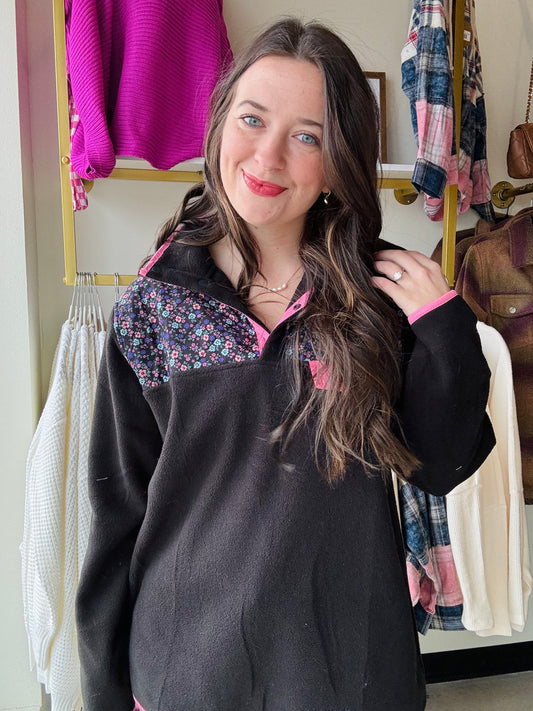 Stay cozy and stylish with our Floral Pullover! Made with black fleece and adorned with a beautiful floral print and pink details, this pullover is perfect for any casual occasion. Snaps make it easy to put on and take off.&nbsp;