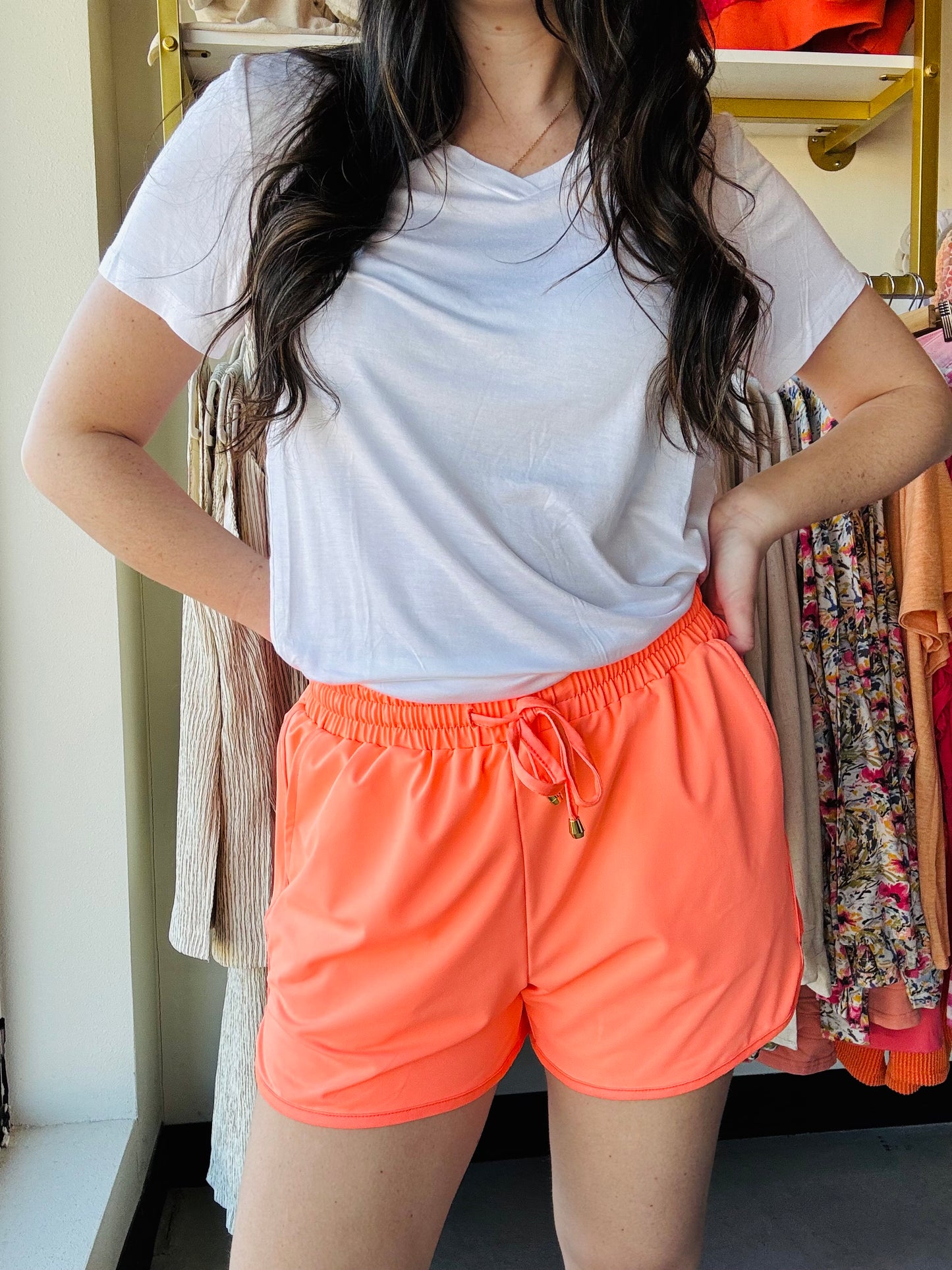 These mid-rise solid neon coral shorts are so perfect for the spring and summer and even to wear in to the fall! Get the effortless yet chic look with these shorts. They feature a mid-rise, tie waist drawstring, &amp; side pockets. These are a relaxed fit.