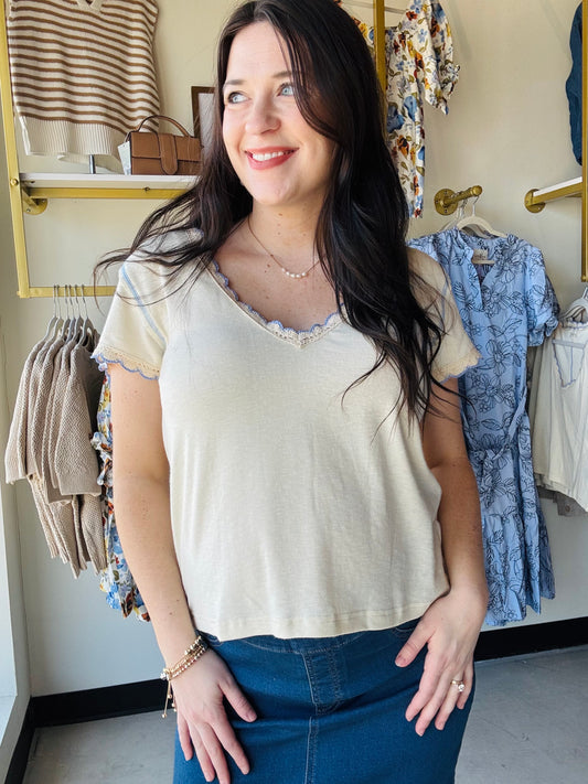 Designed in a V-neck short sleeve regular fit top crafted from soft cotton jersey. Featuring delicate contrast trim along the neckline and sleeve edges, this piece adds a subtle feminine touch to a classic silhouette. Finished with vintage washing for a naturally soft, lived-in feel, the lightweight fabric offers everyday comfort with effortless styling versatility. A timeless solid essential perfect for layering or wearing on its own.
