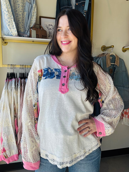 POL

Embrace effortless spring style with this charming lace trim patch top. Delicate lace sleeves and pink accents frame a beautiful floral pattern, while functioning buttons offer easy layering versatility. The oversized silhouette delivers that coveted relaxed fit perfect for casual days and breezy weather. Whimsical details meet everyday comfort in a piece that feels as good as it looks.