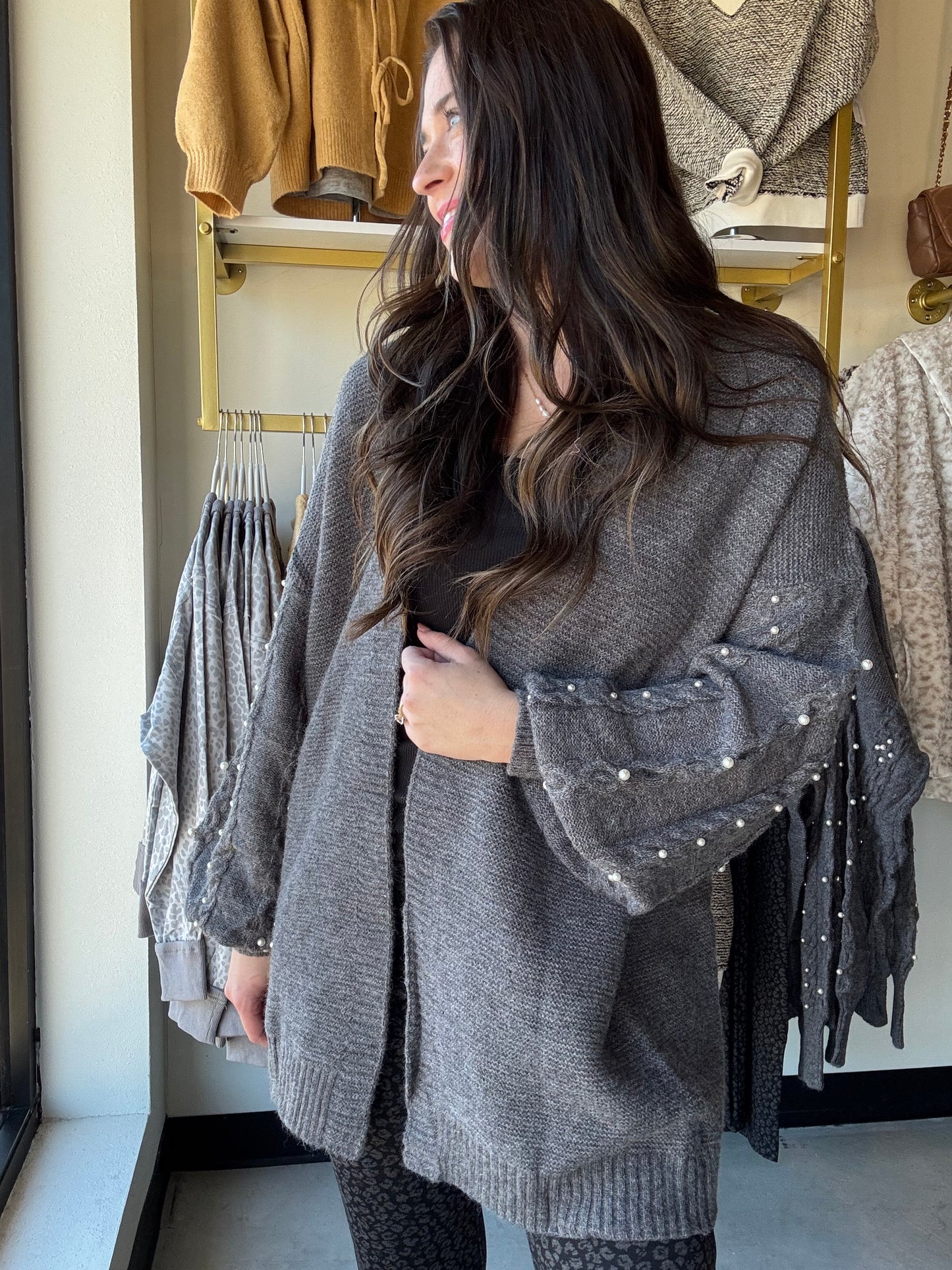 Umgee

Wrap yourself in cozy charm with the Charcoal Pearl Sleeve Cardigan. This playful open-front piece features delicate pearl buttons and long sleeves that add a touch of elegance to your everyday look. Perfect for layering, it effortlessly blends comfort with style, making it your new go-to for cooler days and casual outings.