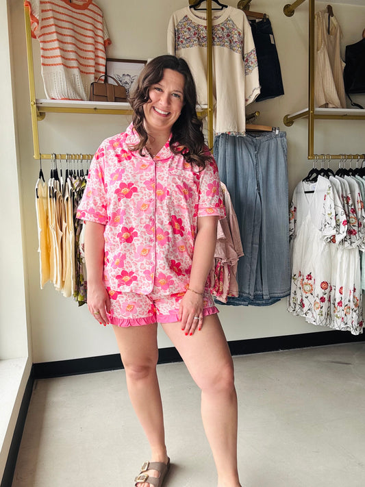 Jess Lea

Elevate your sleepwear game with the Spotted in Bloom Ruffle Pajama Set. The long-sleeve top showcases a captivating blend of pink blooms and leopard spots, finished with a polished collar and practical chest pocket. Shorts feature playful ruffled hems and a sweet bow detail that adds instant charm. Whether you're settling in for a restful night or lounging through lazy mornings, this set delivers the perfect balance of snug and sassy—because your pajamas deserve to be just as fabulous as you are.