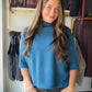 Understated. Elevated. Endlessly wearable. The &nbsp;Teal Soft Mockneck Sweater by Rain &amp; Rose is the kind of sweater your wardrobe has been waiting for — a modern mock neck silhouette in rich, teal color with softly pleated elbow sleeves that add just the right amount of interest. Lightweight knit that drapes beautifully, goes with everything, and looks polished without trying.

Why You'll Love It

Modern mock neck — clean, minimal, and always in style
Soft pleated elbow sleeves — subtle detail that se