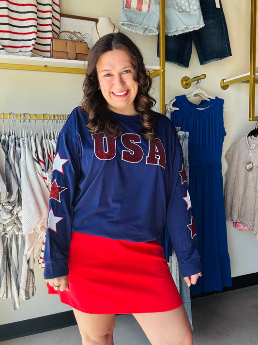 Ignite your patriotic spirit with this navy long-sleeve top featuring bold sequin "USA" lettering and embroidered star sleeves. Perfectly festive and effortlessly stylish, it’s the ultimate statement piece for every American celebration.