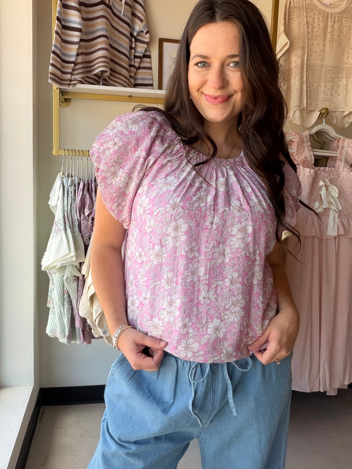 Feminine, flirty, and made for warm-weather dressing — the Pink Floral Puff Sleeve Top by Umgee is the kind of piece that makes getting dressed feel effortless. A vibrant floral print meets a relaxed, flowy silhouette, while short puff sleeves and delicate pleat and gathered details add a romantic, editorial touch. Wear it tucked into your favorite denim or let it flow for an easy, breezy look.

Details:

Floral print throughout
Short puff sleeves with lined construction
Round neckline with gathered detail
