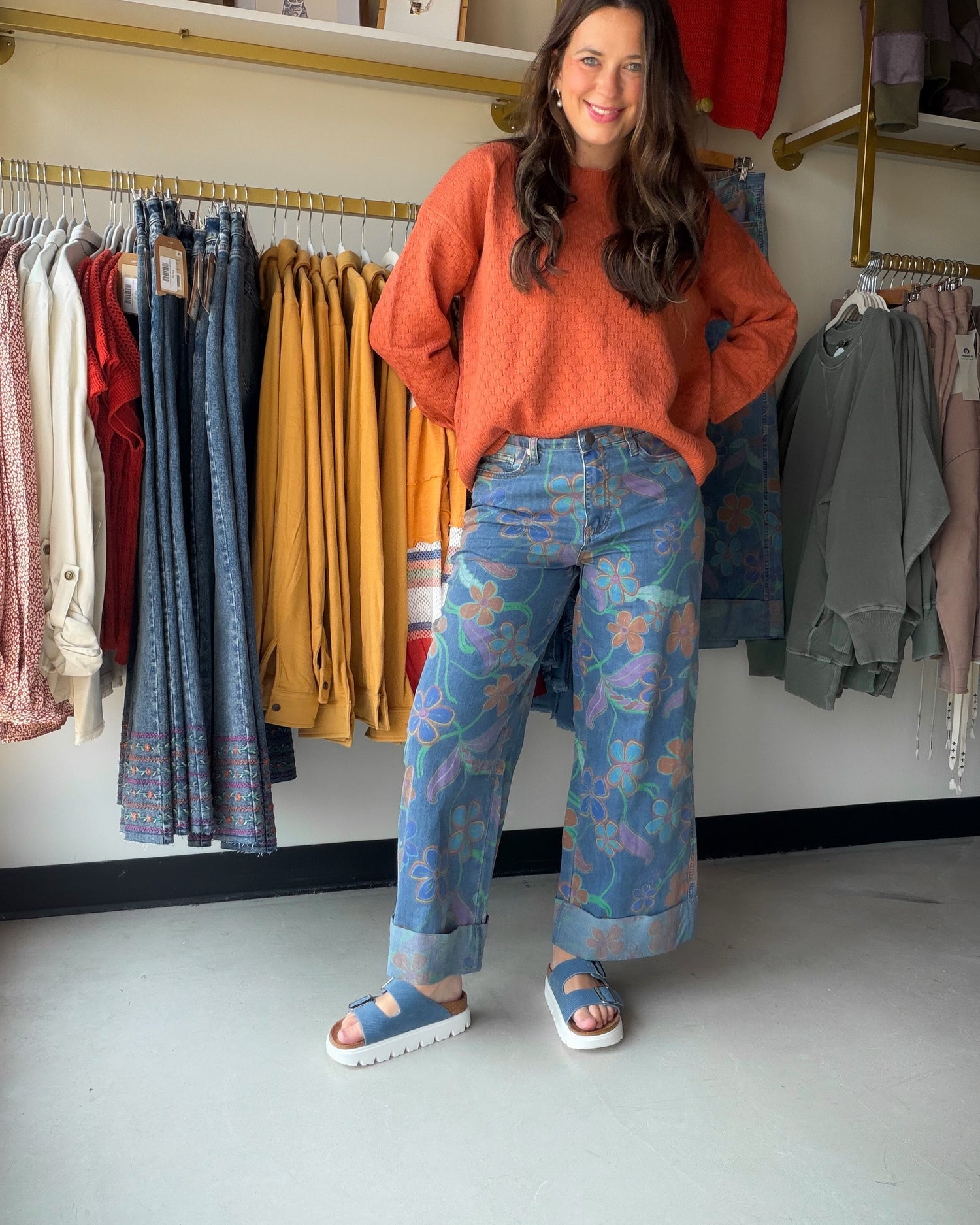 Orange long-sleeve oversized sweater paired with a floral printed wide leg denim pants that have a cuffed bottom
