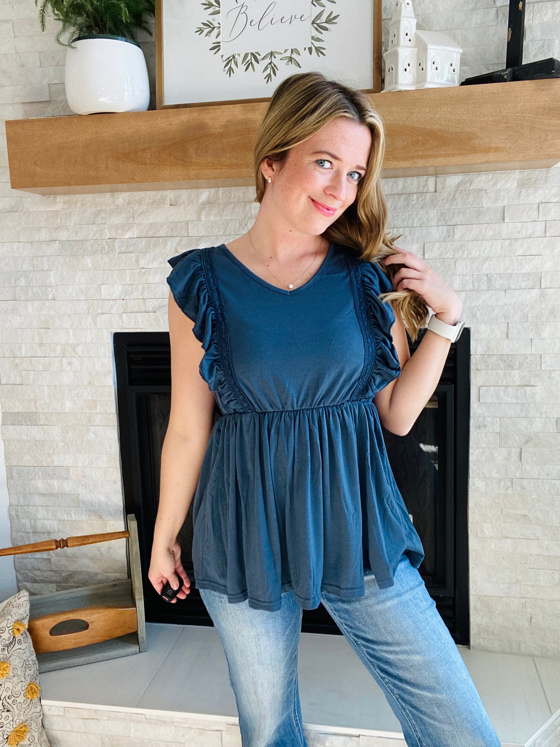 Look fashionable and feel confident wearing this navy ruched peplum tank top. The flattering silhouette is perfect for pairing with light or white denim. Flutter accents add a touch of femininity to the design. It's a great choice for any occasion.