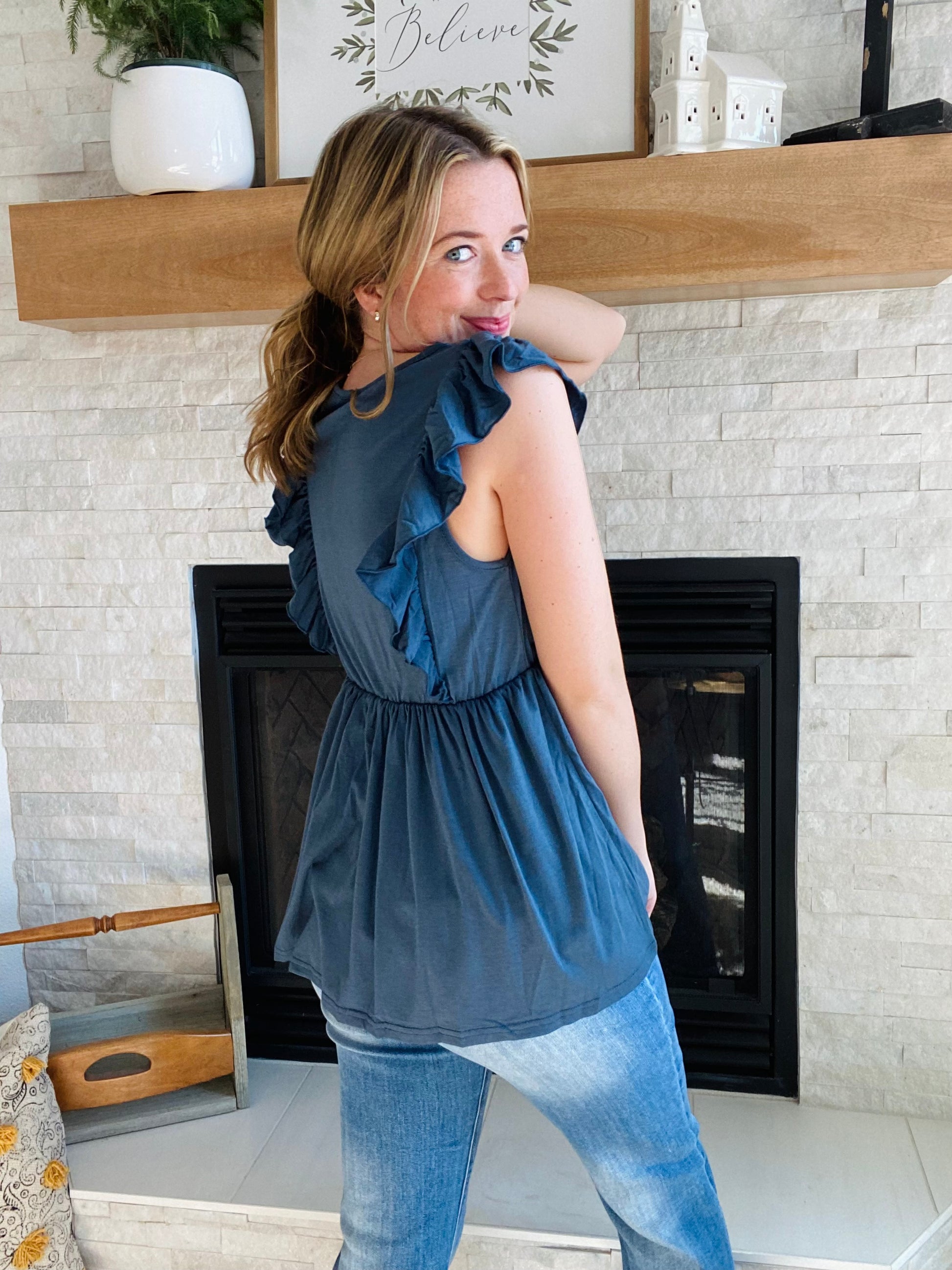 Look fashionable and feel confident wearing this navy ruched peplum tank top. The flattering silhouette is perfect for pairing with light or white denim. Flutter accents add a touch of femininity to the design. It's a great choice for any occasion.